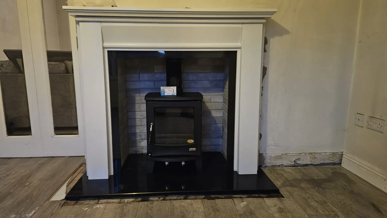 A finished stove and fireplace installation: white mantel, black granite hearth and solid fuel stove